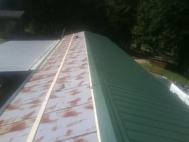 Old rusted panels beside newly installed green metal roofing — Wind Damage Roof Repair by Roofing Brothers in Pinnacle